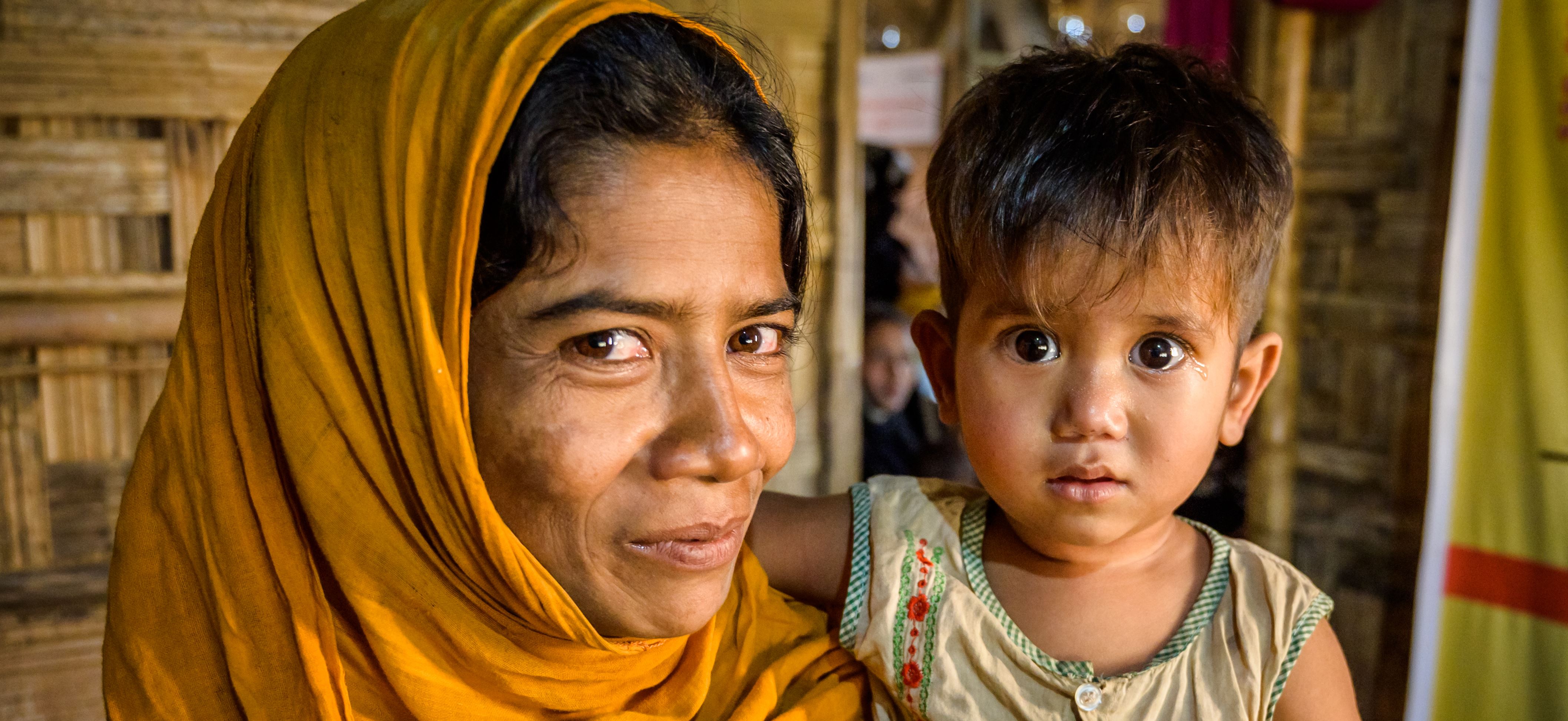Madre e suo figlio, rifugiati Rohingya, fuggiti in Bangladesh, guardano nella telecamera, più felici ora che il bambino è guarito dalla malnutrizione