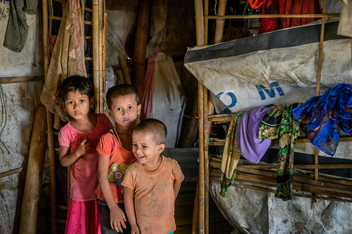 Three children in front of make-shift home in a refugee camp in Bangladesh