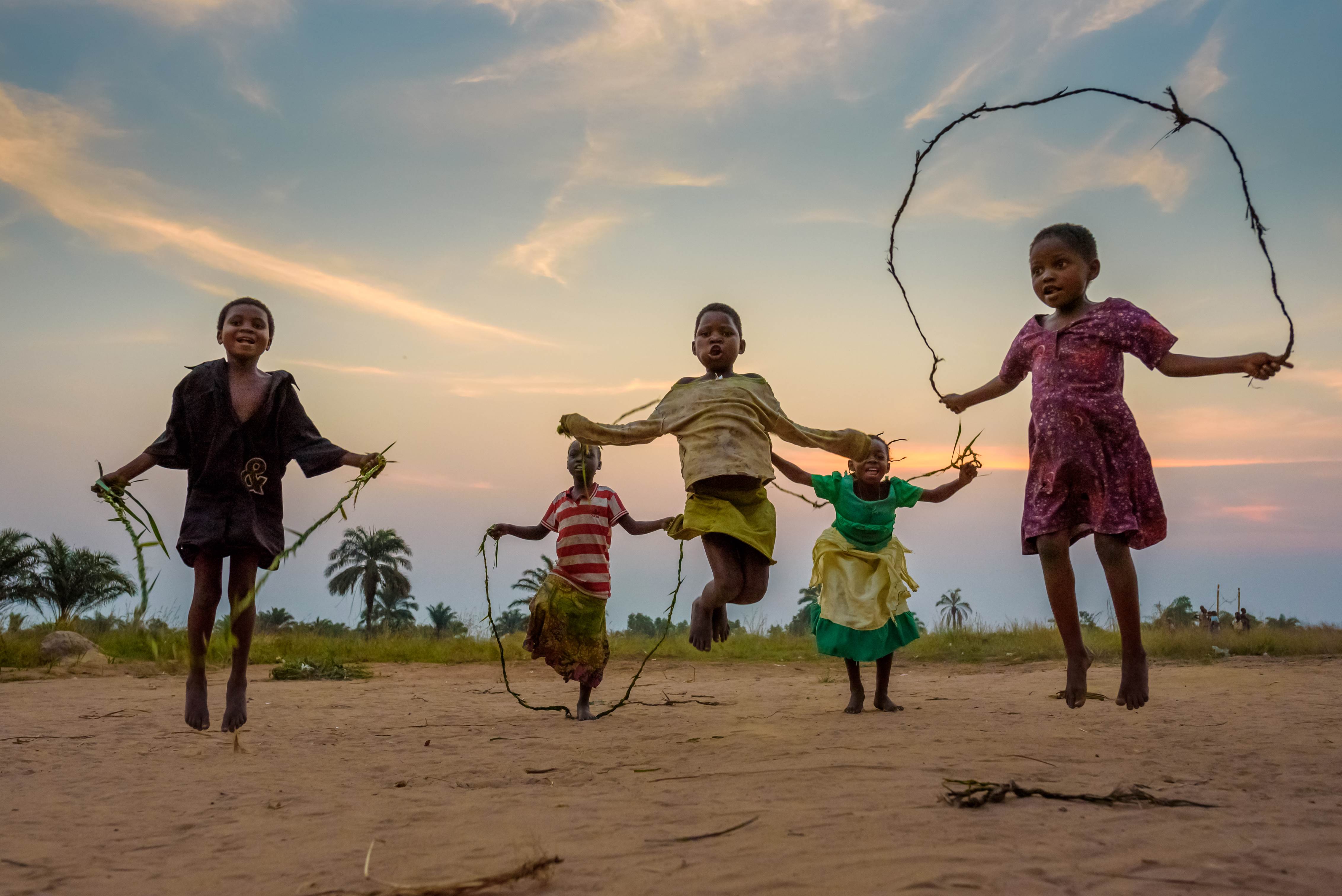 5 bambini si divertono a saltare sullo sfondo di un tramonto in uno spazio a misura di bambino (CFS) nella Repubblica Democratica del Congo