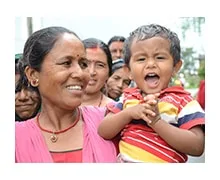 Donna nepalese che tiene in braccio un bambino sorridente