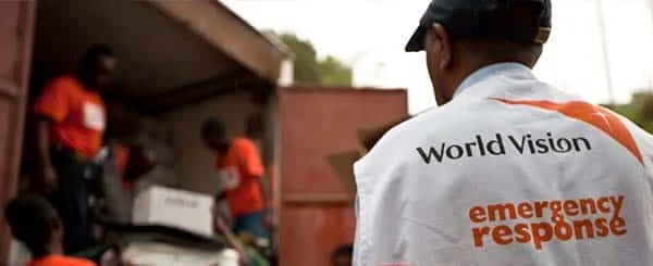 Operatore world visione coinvolto in attività di risposta alle emergenze con altri membri del team che caricano o scaricano aiuti da un camion