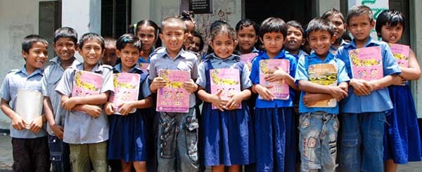 Gruppo di bambini sorridenti e in posa, che tengono tra le mani un libro di scuola