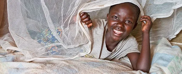 Bambina sorridente sotto una zanzariera