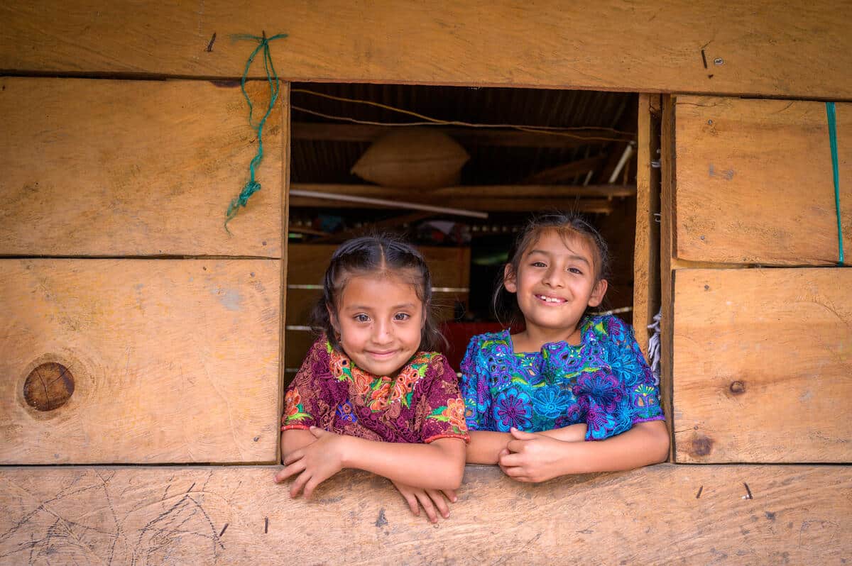 Samanta, 6 anni, (a sinistra) e Jaylini, 8 anni, sbirciano fuori dalla finestra della casa della loro famiglia. La loro famiglia ha una prospettiva economica migliore grazie al dono dei maiali attraverso il programma Gift Catalog di World Vision. Un dono di animali può aiutare i genitori in difficoltà a provvedere meglio alla propria famiglia offrendo una fonte costante di nutrimento tanto necessario da uova, carne o latte. Nel corso del tempo, le famiglie possono anche aumentare il proprio reddito vendendo la prole dei loro animali. In Alta Verapaz, i maiali sono l’opzione preferita poiché prosperano alle alte quote della zona e portano profitti maggiori rispetto ad altri animali. Juan Carlos Chavac, che supervisiona la distribuzione del Catalogo dei regali in Guatemala, afferma che allevare maiali aumenta la resilienza di una famiglia aiutandola a guadagnare un reddito costante, che consente loro di mettere da parte i soldi per eventuali difficoltà o emergenze che potrebbero sorgere. Ilse dice della prospettiva di ottenere sicurezza attraverso l’allevamento di maiali: “Quando sono stata selezionata”, dice, “mi sono sentita davvero felice di essere sulla lista”. Nel maggio 2022 Ilse ha portato a casa il suo primo maialino. Ha condiviso le conoscenze che aveva acquisito sulla pulizia del rifugio e sull’alimentazione dei maiali con le sue due figlie più grandi. Ilse si occupa ancora della maggior parte delle cure, ma le sue due figlie più grandi l'aiutano. Le famiglie che ricevono gli animali del Catalogo regali sono anche incoraggiate a unirsi a un gruppo di risparmio, cosa che ha fatto Ilse. Ora la combinazione di maiali e gruppo di risparmio ha aiutato Ilse e suo marito Marco a potersi permettere ciò che prima non potevano permettersi: “Prima non potevo comprare frutta o verdura per le mie figlie”, dice Ilse. “Ora [noi] possiamo avere una varietà di cibi. Posso cucinare pasti diversi ogni giorno.” Continuando a riflettere sui cambiamenti positivi, afferma: “Prima era difficile. . . Prendevo in prestito dei soldi o chiedevo alle mie cognate se avevano dei soldi a casa loro”. Vedi D145-0233 - La catena della benedizione per la storia completa.