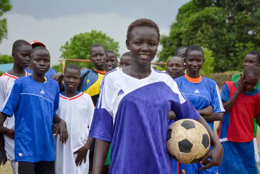 Gruppo di bambine che giocano a calcio, rappresentando l'empowerment femminile e il sostegno di World Vision per l'uguaglianza di genere attraverso lo sport.