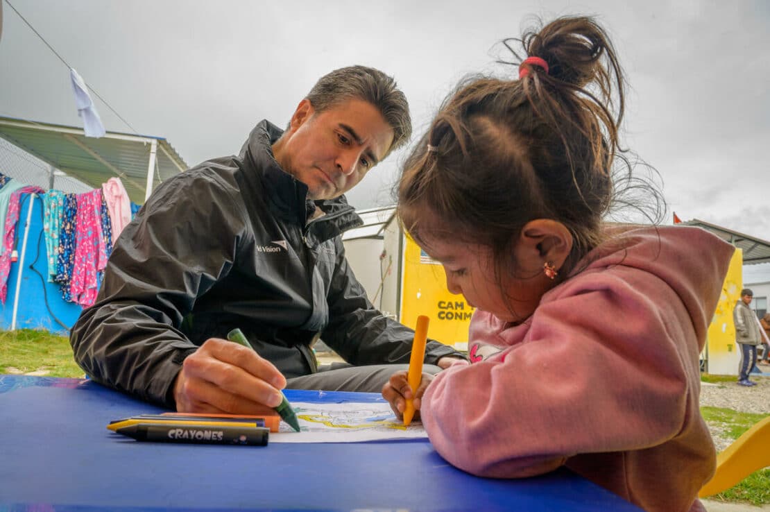 Il presidente e amministratore delegato di World Vision U.S., Edgar Sandoval, Sr. ha parlato e colorato con una bambina di nome Sofia presso lo spazio Child Friendly del CAS di Berlino (centro di rifugio e attenzione). Il rifugio si trova a Berlino, a circa 40 miglia (64,3 km) da Bucuramanga, la quarta città più grande della Colombia. Si trova a circa 11.000 piedi (3.400 km) sulle Ande orientali. Il rifugio ha lo scopo di proteggere, curare e sostenere l’intera popolazione migrante in transito. World Vision gestisce il rifugio in coordinamento con il Gruppo interagenzia sui flussi migratori misti (GIFMM) e con altri partner come la Croce Rossa colombiana e altre organizzazioni umanitarie e autorità nazionali e locali. Hanno iniziato ad operare nel luglio 2021. Al 30 settembre 2023 avevano servito più di 58.000 pasti inclusi colazione, pranzo e cena. Erni vuole che suo figlio diventi un giocatore di baseball. Suo padre era un giocatore di baseball professionista. Ha giocato in 2a base e in campo centrale. La sua morte è stata causata da un infarto. La sua situazione economica divenne davvero grave. Vengono da La Guaira, Venezuela. Hanno camminato per 2 settimane e sono arrivati ​​ieri alle 18:00. Hanno bisogno di soldi per i biglietti dell'autobus fino al confine con l'Ecuador. Sono in viaggio per il Perù. Qui, le persone che arrivano dal Venezuela (rifugiati, migranti e rimpatriati colombiani) troveranno uno spazio sicuro e protetto 7 giorni su 7 - 24 ore su 24, dove potranno trovare assistenza di primo soccorso, alloggio, idratazione, pasti caldi, protezione per le persone non accompagnate o bambini separati, Spazio a Misura di Bambino e ristabilimento dei contatti familiari. Si tratta di una rotta che continua a testimoniare il passaggio di migranti disperati che hanno trascorso giorni senza mangiare né dormire. È un viaggio di 199 chilometri tra Cúcuta, al confine venezuelano, e Bucaramanga. Questo è il punto in cui molti migranti decidono tra continuare o tornare indietro, tra la vita o la morte. Questa rotta è diventata la via per fuggire dalla fame e dalla disperazione. Il rifugio è gestito da World Vision e si trova nel punto più alto